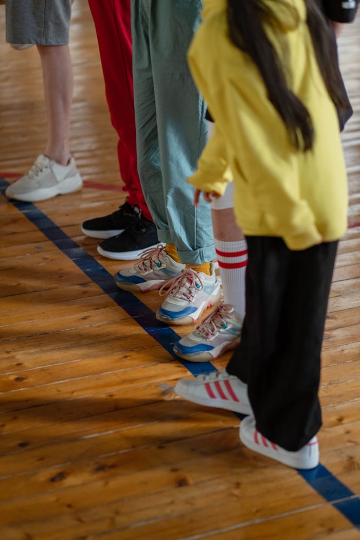 Group of children lined up in a gym wearing colorful sneakers, ready for physical activity.