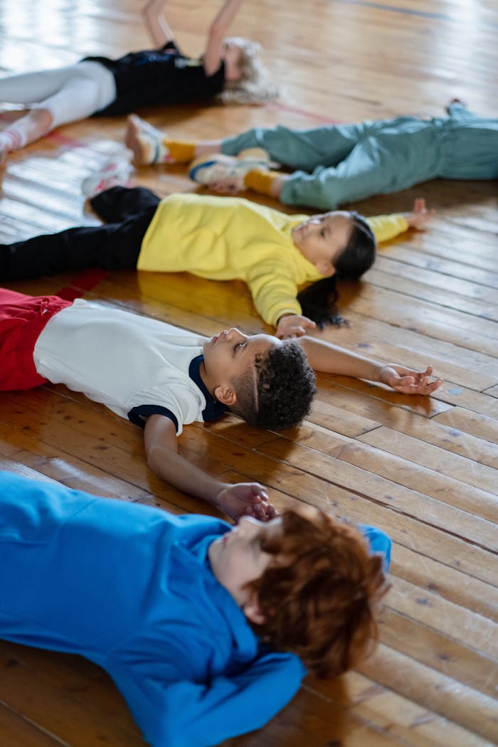 Diverse group of children relaxing on a gym floor during a physical education class.